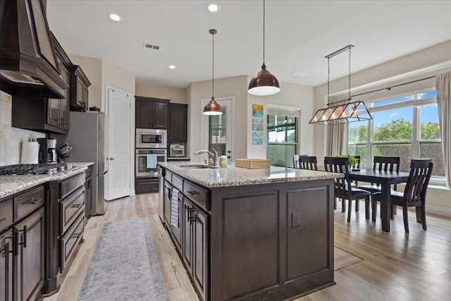 kitchen featuring dark brown cabinetry, visible vents, pendant lighting, premium range hood, and stainless steel appliances