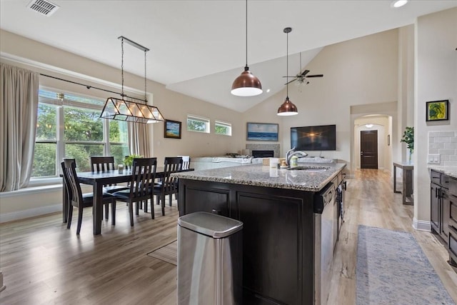 kitchen featuring a fireplace, arched walkways, a ceiling fan, open floor plan, and visible vents