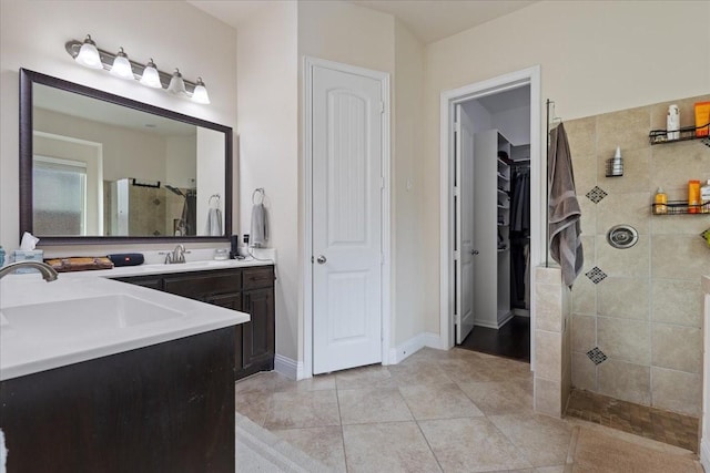 full bathroom with a sink, a tile shower, and double vanity