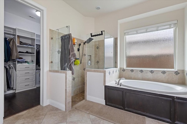 bathroom featuring a walk in closet, walk in shower, a garden tub, and visible vents