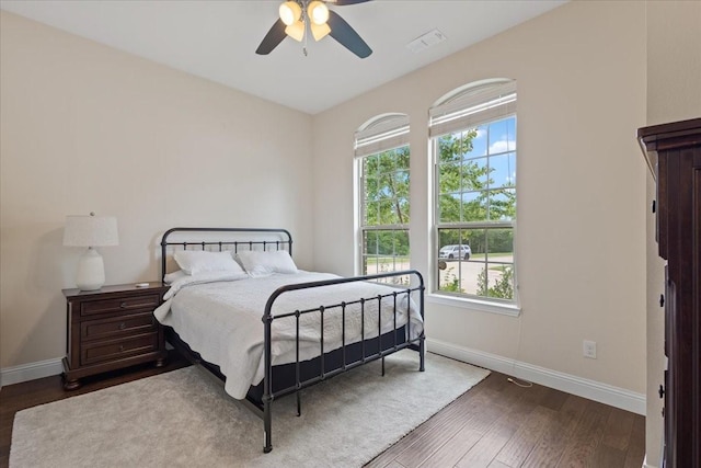 bedroom with baseboards, ceiling fan, wood finished floors, and visible vents