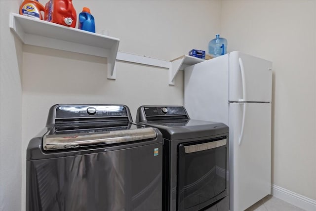 clothes washing area with tile patterned floors, baseboards, laundry area, and washing machine and dryer