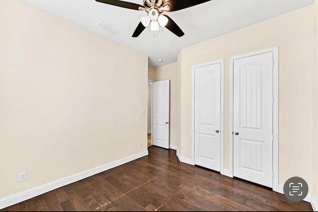 unfurnished bedroom featuring baseboards, ceiling fan, dark wood-style floors, and visible vents