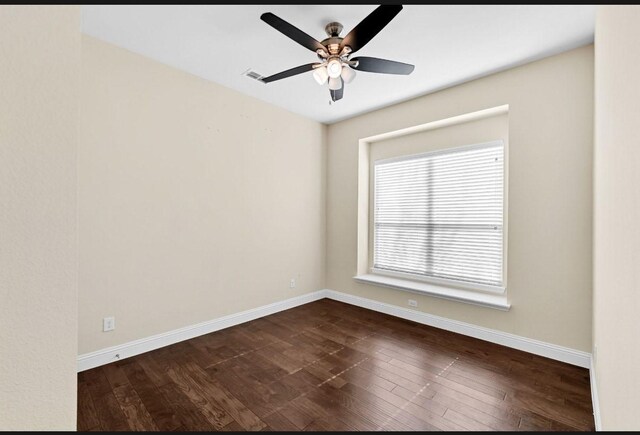 unfurnished room with dark wood-style flooring, baseboards, visible vents, and ceiling fan