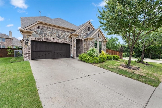 french country inspired facade with fence, an attached garage, stone siding, a front yard, and concrete driveway