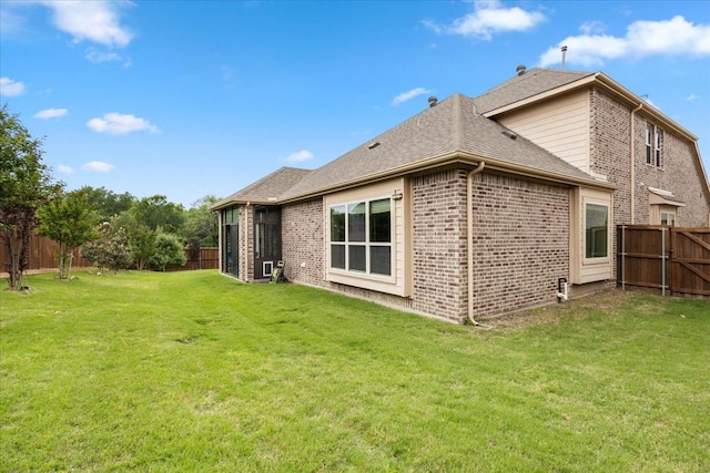 rear view of house featuring a fenced backyard, a yard, and brick siding