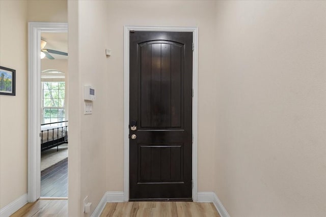 foyer entrance with a ceiling fan, baseboards, and light wood finished floors