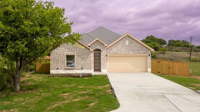 french country style house featuring roof with shingles, a front lawn, brick siding, a garage, and driveway