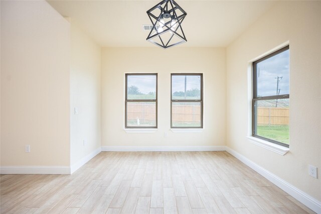 spare room with light wood-style floors, baseboards, and visible vents