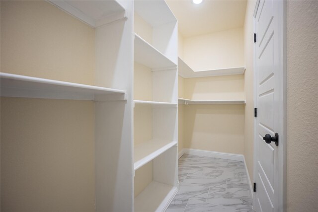 walk in closet with marble finish floor
