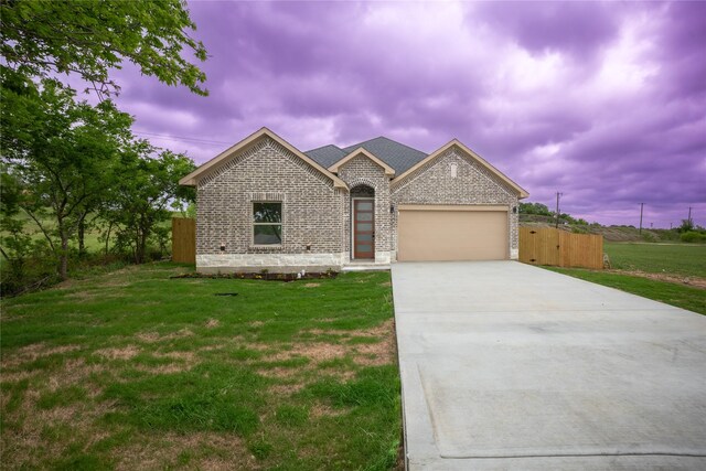 view of front of property featuring a garage, fence, a front yard, brick siding, and driveway