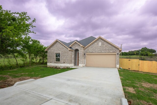 view of front of house featuring a garage, fence, a front yard, brick siding, and concrete driveway