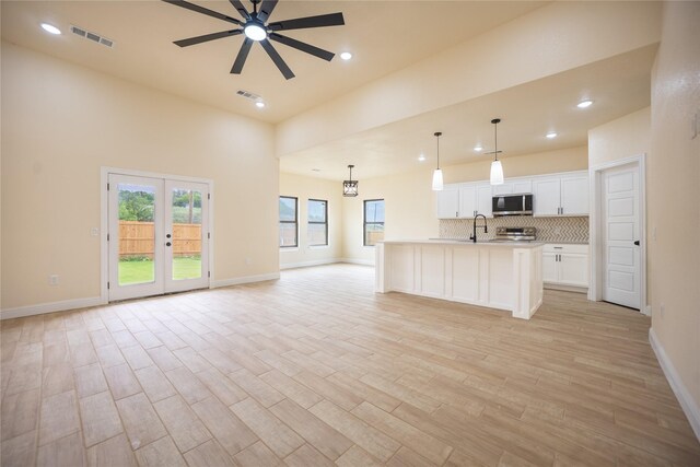 kitchen featuring visible vents, open floor plan, white cabinetry, stainless steel microwave, and a ceiling fan