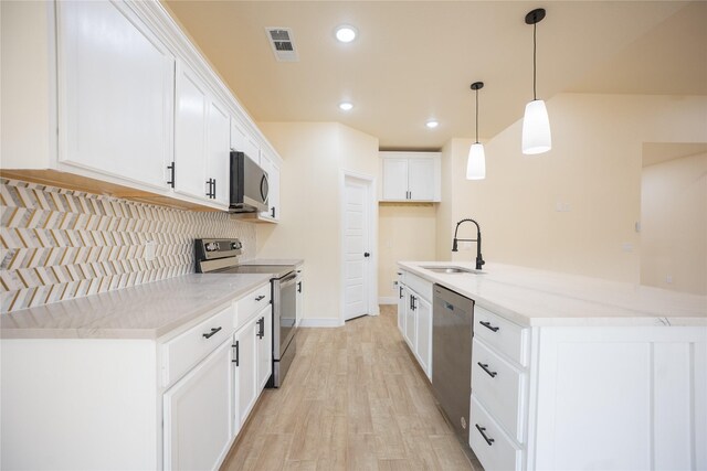 kitchen with visible vents, light wood-style floors, a sink, backsplash, and stainless steel appliances
