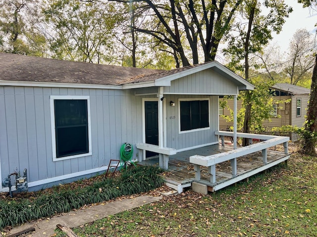 view of front of house with a wooden deck and roof with shingles