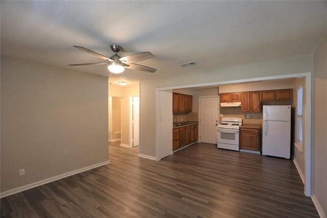 kitchen featuring white appliances, brown cabinetry, baseboards, under cabinet range hood, and visible vents
