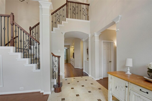 entrance foyer featuring stairs, arched walkways, decorative columns, and a towering ceiling