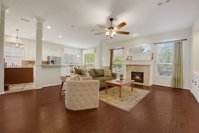 living room with a ceiling fan, visible vents, dark wood-style floors, and a fireplace