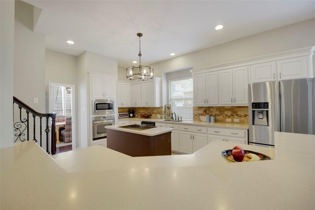 kitchen featuring decorative backsplash, light countertops, a chandelier, stainless steel appliances, and white cabinetry