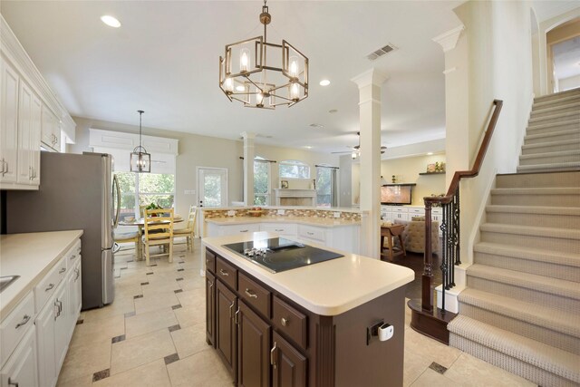 kitchen with dark brown cabinetry, black electric stovetop, light countertops, a center island, and freestanding refrigerator