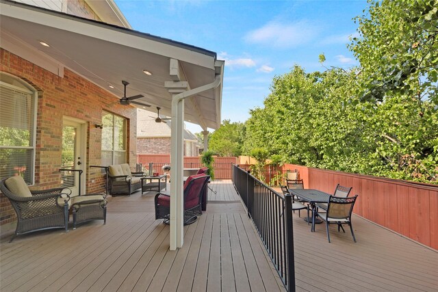 wooden terrace with an outdoor living space, outdoor dining area, ceiling fan, and fence