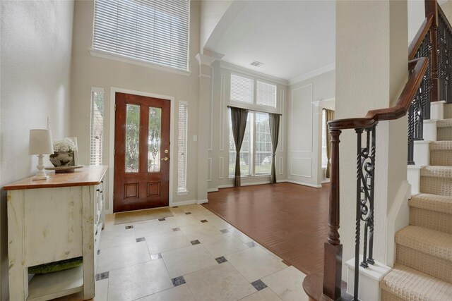 entryway featuring arched walkways, a high ceiling, stairway, light tile patterned floors, and ornamental molding