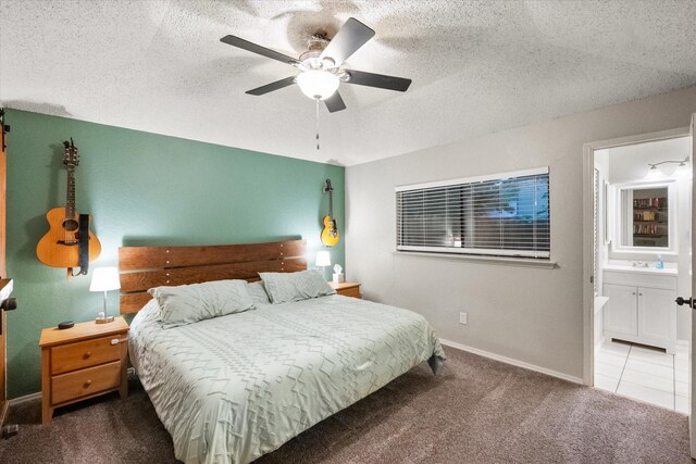 bedroom featuring carpet floors, baseboards, a textured ceiling, a sink, and ensuite bath
