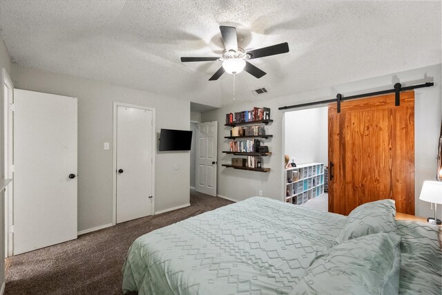 carpeted bedroom featuring baseboards, a textured ceiling, a barn door, and visible vents