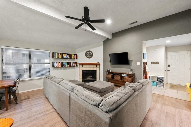 living room featuring visible vents, baseboards, a tile fireplace, a ceiling fan, and light wood-style flooring