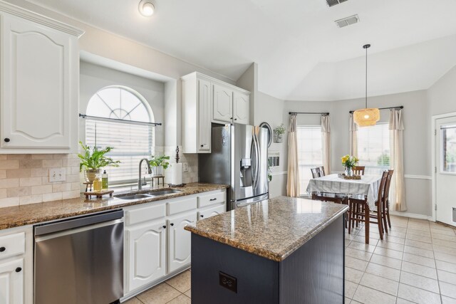kitchen featuring light tile patterned flooring, appliances with stainless steel finishes, a sink, tasteful backsplash, and vaulted ceiling