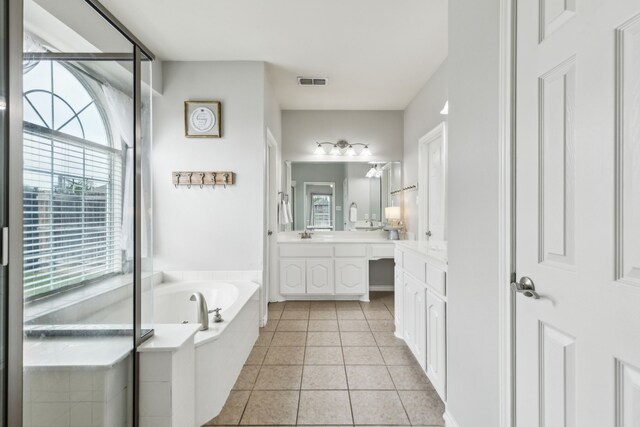 bathroom with visible vents, a healthy amount of sunlight, a garden tub, and vanity
