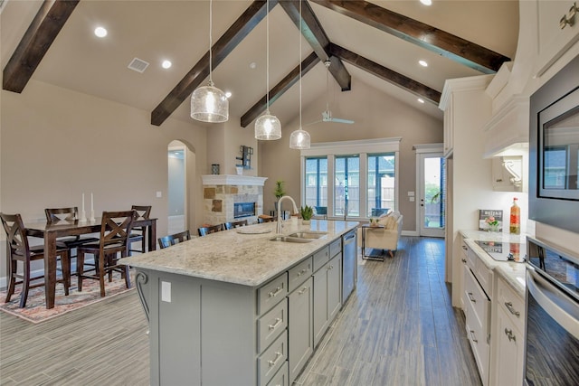 kitchen with stainless steel appliances, beam ceiling, gray cabinetry, and a sink