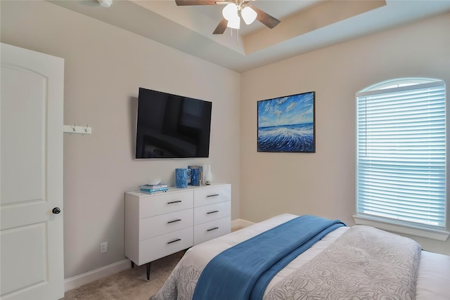 bedroom featuring light colored carpet, a ceiling fan, baseboards, and multiple windows