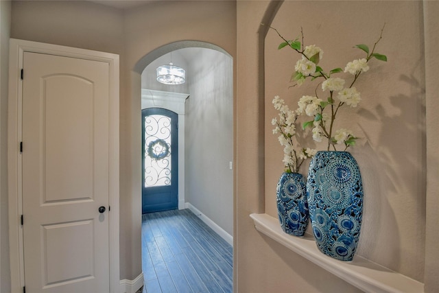 entrance foyer with baseboards, arched walkways, and wood finished floors