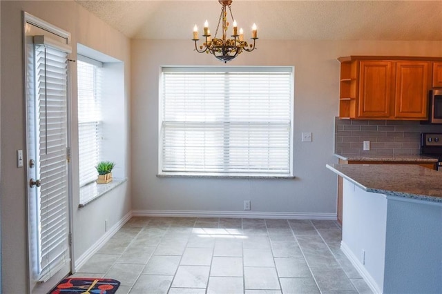 10408 Ambergate Ln, Frisco, TX 75035 - kitchen featuring range with electric cooktop, stone counters, brown cabinets, stainless steel microwave, and an inviting chandelier