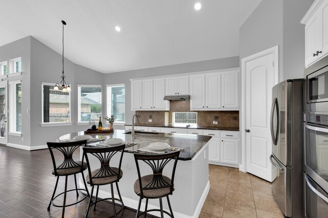 kitchen featuring baseboards, a chandelier, a sink, backsplash, and stainless steel appliances