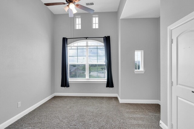 unfurnished room featuring a healthy amount of sunlight, a ceiling fan, carpet flooring, and visible vents