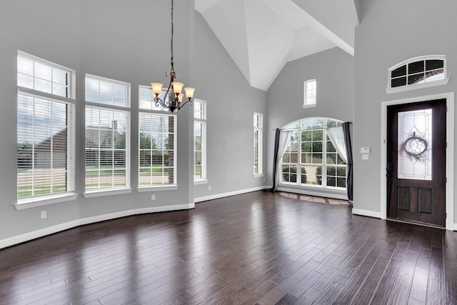 foyer featuring high vaulted ceiling, an inviting chandelier, a wealth of natural light, and dark wood-type flooring