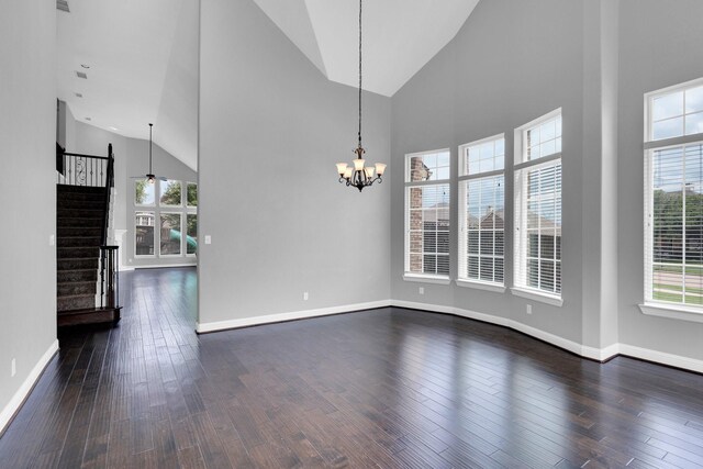 unfurnished dining area featuring dark wood-style flooring, high vaulted ceiling, a notable chandelier, and a healthy amount of sunlight