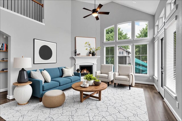 living room featuring ceiling fan, a warm lit fireplace, high vaulted ceiling, and a healthy amount of sunlight