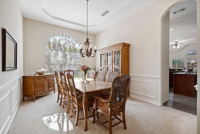 dining area with light colored carpet, arched walkways, a decorative wall, and visible vents