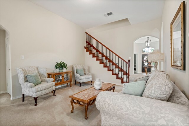 living room featuring light carpet, arched walkways, baseboards, visible vents, and stairway