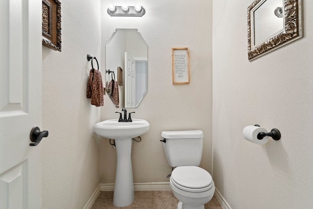 bathroom with toilet, baseboards, and tile patterned flooring