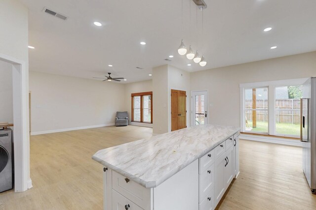 kitchen with washer / dryer, a ceiling fan, light wood finished floors, and visible vents