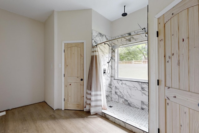 bathroom featuring a marble finish shower and wood finished floors
