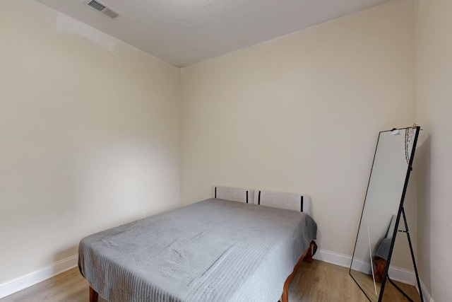 bedroom featuring baseboards, light wood-style flooring, and visible vents