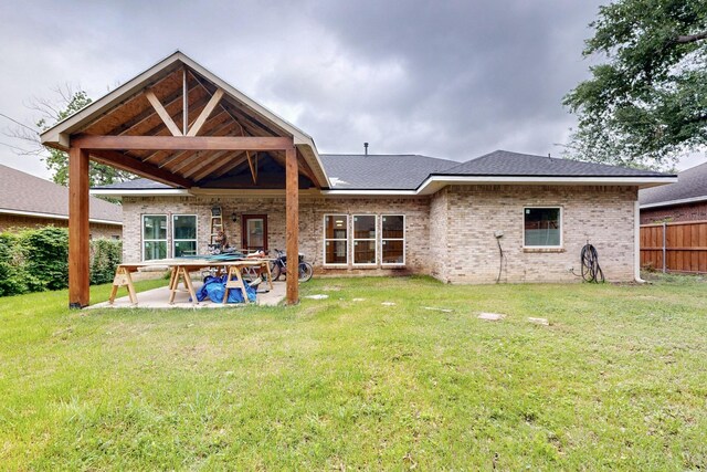 rear view of property featuring a patio, a lawn, fence, and brick siding