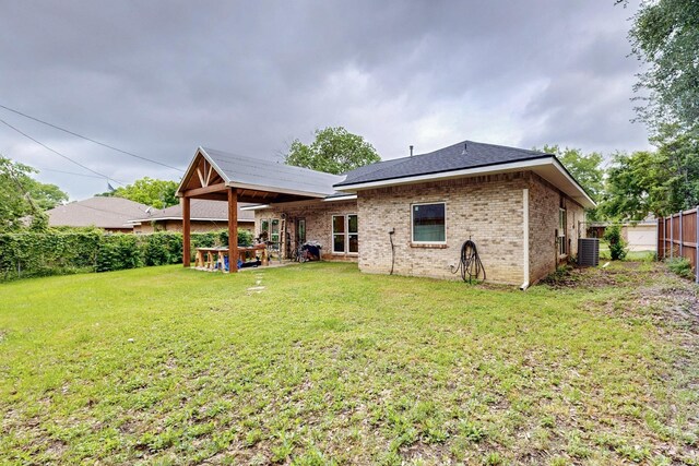rear view of property with brick siding, fence, a yard, and cooling unit