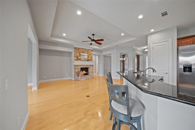 kitchen with a fireplace, baseboards, ceiling fan, a tray ceiling, and stainless steel built in refrigerator