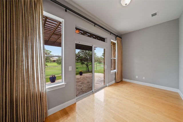 doorway with baseboards, light wood-style flooring, and visible vents